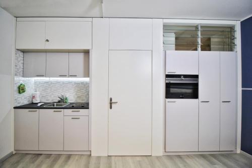 a white kitchen with white cabinets and a sink at Ferien am Luganer See mit Seesicht in Bissone