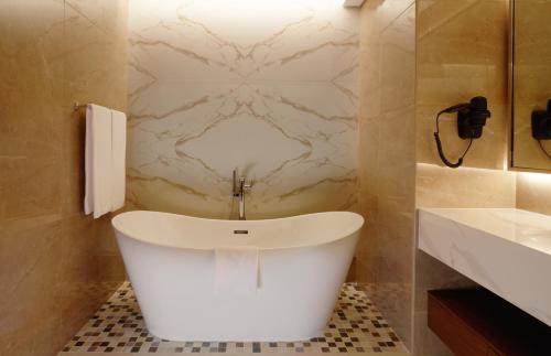 een badkamer met een wit bad en een wastafel bij Royal M Al Aqah Beach Resort by Gewan in Al Aqah