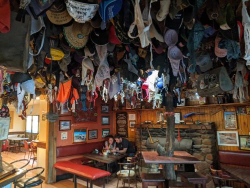a bar with a bunch of hats hanging from the ceiling at Kulgera Roadhouse in Kulgera