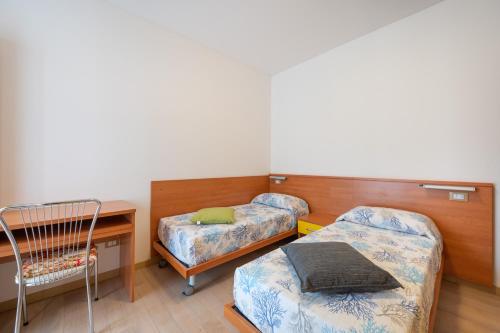 Habitación con 2 camas, escritorio y silla. en Residence Rizzante, en Caorle