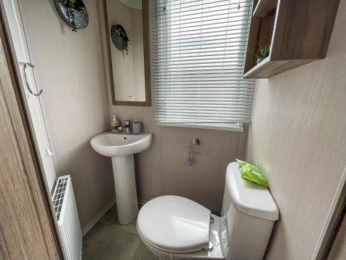 uma pequena casa de banho com WC e lavatório em Beautiful Caravan With Decking And Free Wifi At Highfield Grange Ref 26740wr em Clacton-on-Sea