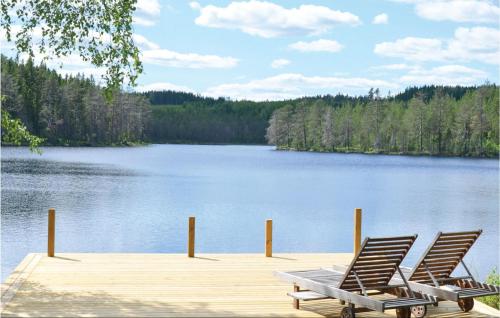 two chairs sitting on a dock next to a lake at Pet Friendly Home In Sunne in Älvsätern