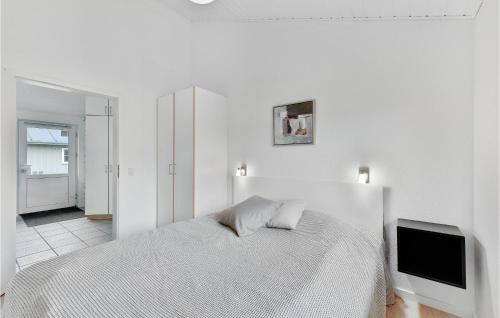 ein weißes Schlafzimmer mit einem Bett und einem Flachbild-TV in der Unterkunft Gorgeous Home In Nrre Nebel With Wifi in Lønne Hede