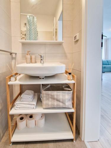 a bathroom with a sink and a shelf with towels at Mirvana Apartments Azur Skyview in Timişoara