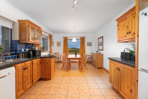 uma cozinha com armários de madeira e uma mesa com cadeiras em Cottage 118 - Cleggan em Cleggan