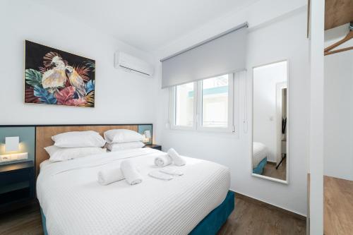 a white bedroom with a large bed and a mirror at Danai & Palm Residential Complexes in Ofrínion