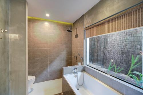 a bathroom with a bath tub and a window at Tanei Angkor Resort and Spa in Siem Reap