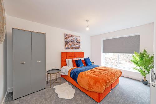 a bedroom with an orange bed and a window at Gospel Heights by Guestz in Heswall