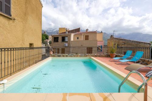 une piscine avec deux chaises et une maison dans l'établissement Casa Pietra - Piscine privative et toit terrasse, à Montegrosso