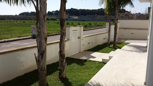 une clôture blanche avec des palmiers dans l'herbe dans l'établissement Case vacanze Iris, à Uggiano la Chiesa
