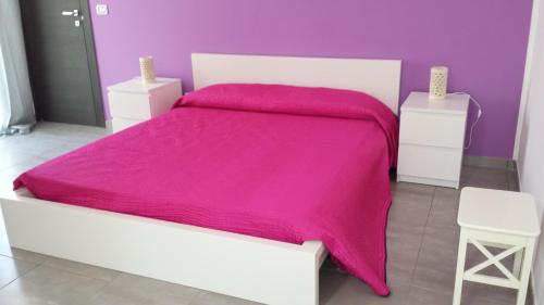 - une chambre violette avec un lit blanc et une couverture rose dans l'établissement Case vacanze Iris, à Uggiano la Chiesa