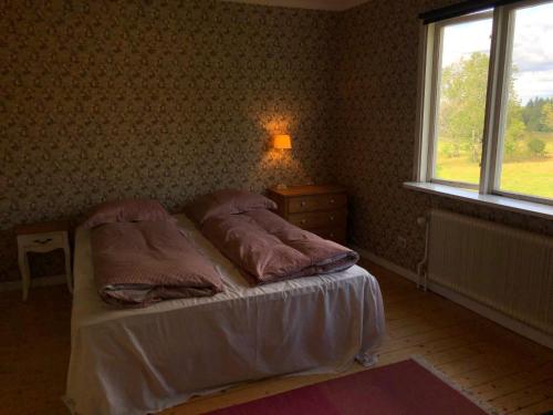 a bedroom with a bed with pillows and a window at Svartarp Gård in Åseda