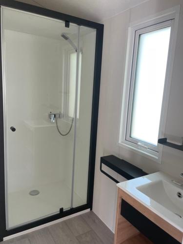 une salle de bain avec douche et lavabo dans l'établissement Camping Les Tourterelles, à Rang-du-Fliers