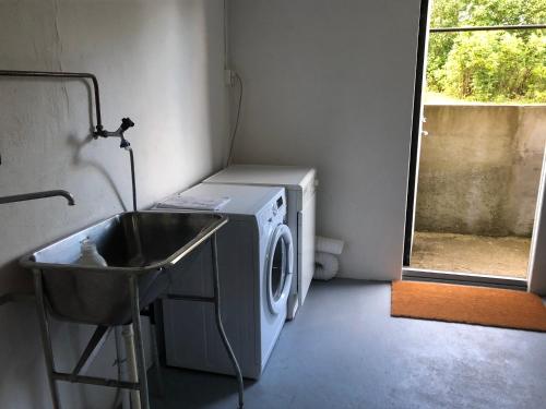 a laundry room with a washing machine and a sink at Svartarp Gård in Åseda