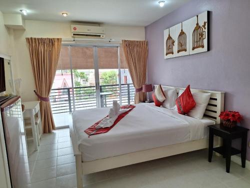 a bedroom with a large white bed with red pillows at Sea Boss Homestay in Kata Beach