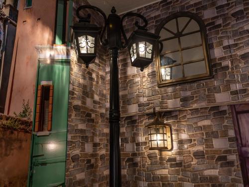 a street light with two lights next to a brick wall at Omotenashi Hostel Miyajima in Hatsukaichi