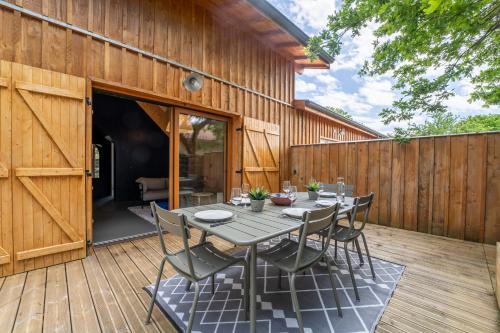 une terrasse en bois avec une table et des chaises. dans l'établissement Wood house - Maison bois atypique à Andernos, à Andernos-les-Bains