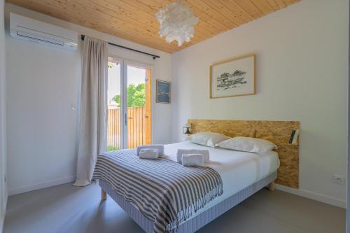 une chambre avec un lit avec des draps blancs et une fenêtre dans l'établissement Wood house - Maison bois atypique à Andernos, à Andernos-les-Bains