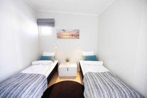 Cette chambre comprend 2 lits et une table. dans l'établissement Nallikari Holiday Village Villas, à Oulu