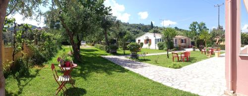 a garden with a table and chairs on the grass at Olga's Garden Apartments in Almiros Beach