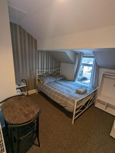 a bedroom with a bed and a table in it at Merginn Guest House in Blackpool