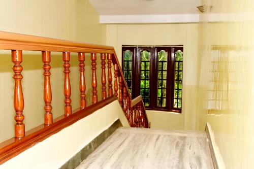 a staircase with a wooden railing and a window at Hotel SV International in Kodaikānāl