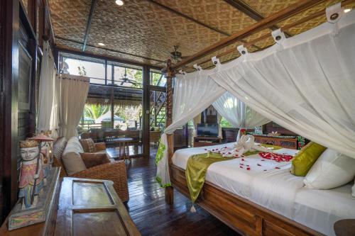 a bedroom with a canopy bed and a living room at Kupu Kupu Private Villa in Ubud