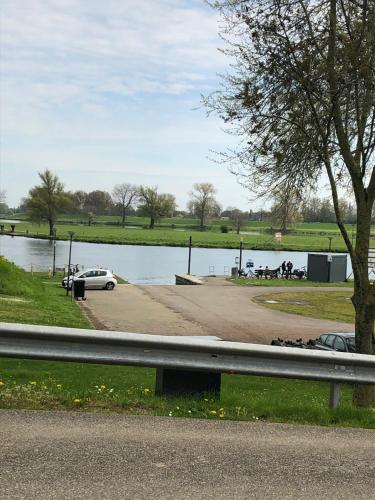 a car parked next to a body of water at Luxe watervilla met eigen aanlegsteiger geschikt voor maximaal 6 personen in recreatiegebied de Gouden Ham in Maasbommel in Maasbommel