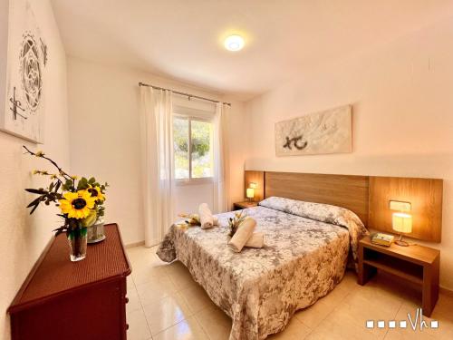 1 dormitorio con 2 camas y un jarrón de flores en VH Costa Blanca - Apartamento Abantos, en Calpe
