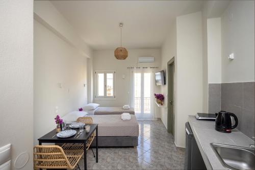 a room with a bed and a table and a kitchen at Bells Rooms and Suites in Ermoupoli