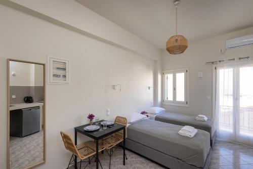 a bedroom with two beds and a table and a kitchen at Bells Rooms and Suites in Ermoupoli
