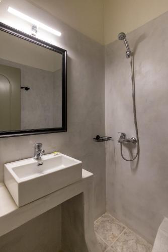 a bathroom with a sink and a mirror and a shower at Bells Rooms and Suites in Ermoupoli