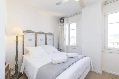 een witte slaapkamer met een groot wit bed met witte kussens bij Le Voeu - Appartement avec vue sur Nice in Nice