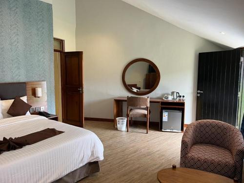 a bedroom with a bed and a mirror and a chair at Morogoro Hotel in Morogoro