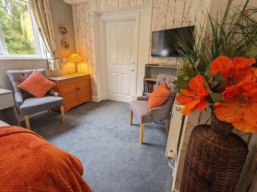 a living room with a vase with orange flowers in it at Foxhills of Shanklin in Shanklin