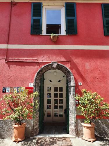 un ingresso a un edificio rosso con due piante in vaso di Boutique Hotel Novecento a La Spezia