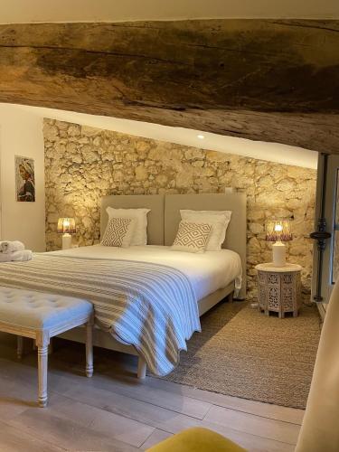 une chambre avec un grand lit et un mur en pierre dans l'établissement La Maison du Clocher, à Saint-Émilion