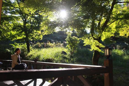 a woman sitting on a bench in a park at 星空に包まれる 森の隠れ家　Amrita Lodge ~stay & retreat~ in Kirishima