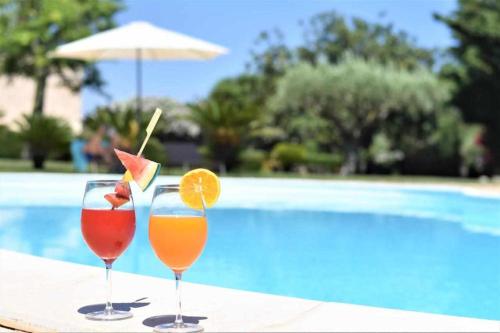 two drinks on a table next to a swimming pool at Torre Dantona Country Hotel 4 stelle in Pozzallo