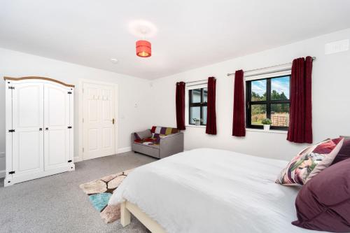 1 dormitorio con cama blanca y cortinas rojas en Cottage 345 - Oughterard, en Oughterard