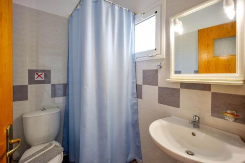 ein Badezimmer mit einem blauen Duschvorhang und einem Waschbecken in der Unterkunft Creta Sun Mochlos in Mochlos
