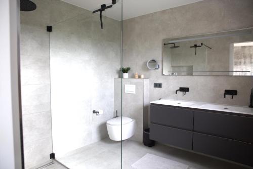ein Bad mit einer Dusche, einem WC und einem Waschbecken in der Unterkunft Peaceful Modern 2 BR Penthouse with nice view in Hesperange