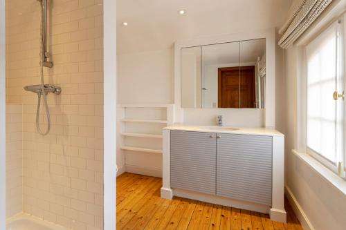 een badkamer met een wastafel en een douche met een spiegel bij Villa Pauline in De Panne