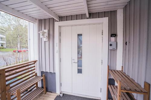 a white door on a porch with two benches at Mukava kellarihuoneisto jossa sauna ja poreallas in Pietarsaari