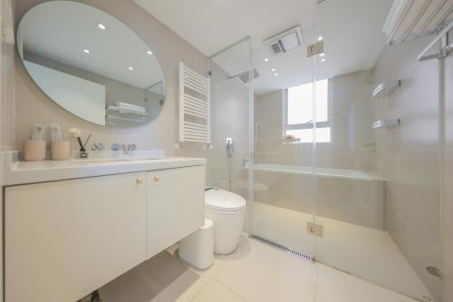 a white bathroom with a toilet and a mirror at Warm Four Bedroom Apartment with Huangpu River View in Shanghai