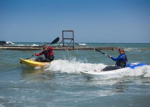 two people are riding in kayaks in the water at Millendreath Beach Resort in Looe