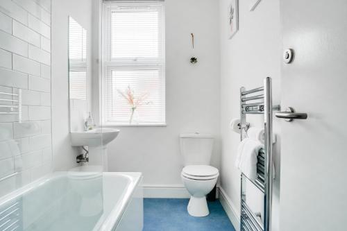 a white bathroom with a tub and a toilet and a sink at Spacious 4 Bedroom house near Leeds CC in Beeston Hill