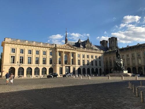 un grand bâtiment avec une statue devant lui dans l'établissement Maison 200m2- 9 chambres avec sdb - 16-18 personnes - séminaire-Proche Centre-Ville-Gare et Arena-terrasse, à Reims