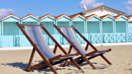 two wooden chairs sitting in the sand on the beach at La casina di Marco in Marina di Pietrasanta