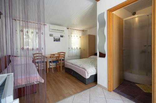 een slaapkamer met een bed en een tafel en stoelen bij Studio Apartman Ema in Gornji Karin